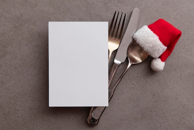 Silver knife fork and spoon with a santa claus red festive hat christmas meal background