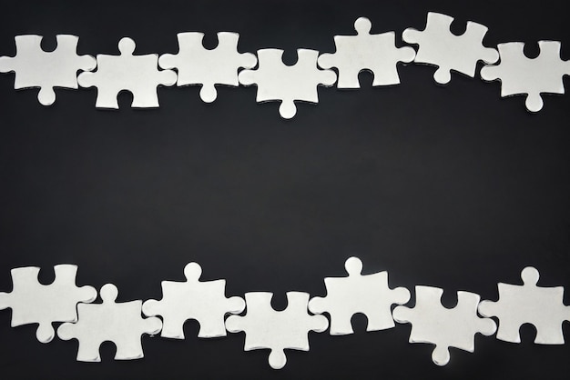 Photo silver metal puzzle pieces arranged as a frame on black background business partnership concept