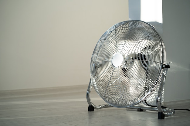 Silver metal ventilation fan on wooden floor at home. copy space