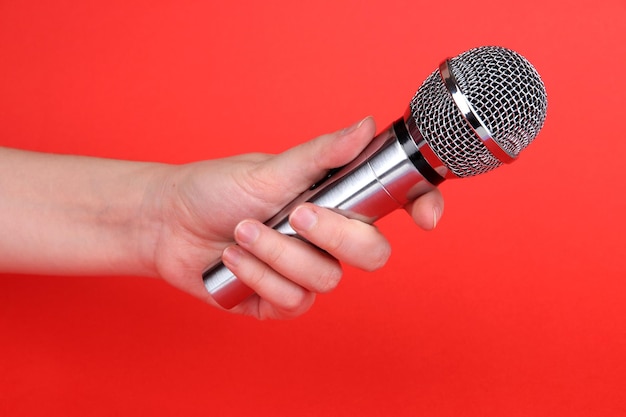 Photo silver microphone in hand on red background