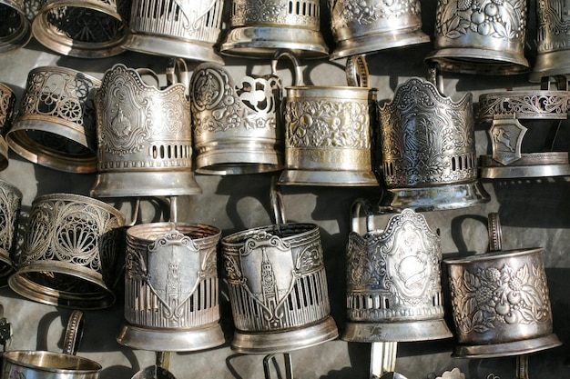 Silver mugs hanging from a wall on a sunny day