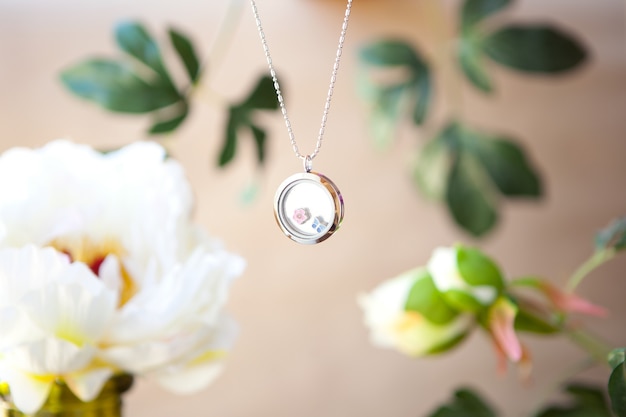 Silver necklace on peonies flower background luxury jewelry\
chains with glass precious metal