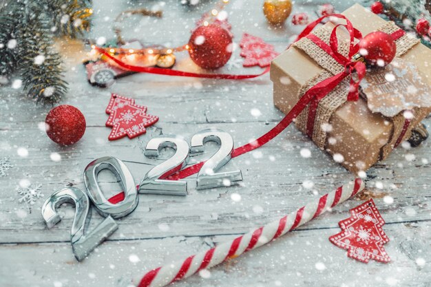 silver numbers 2022 on a wooden background with Christmas decorations and snowflakes