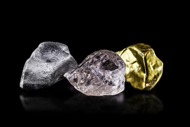Серебряная руда, золотой самородок и необработанный алмаз на черном изолированном фоне.