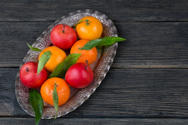 in a silver plate are tangerines and apples