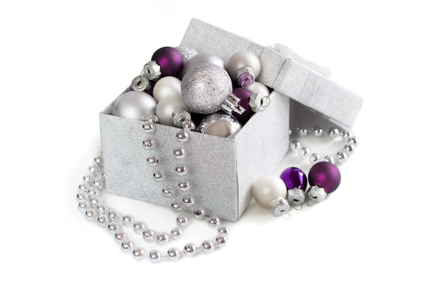 Silver and purple Christmas ornaments in gift box isolated on white close up