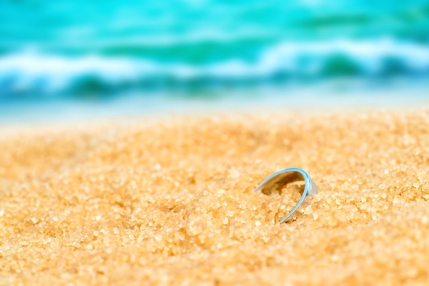 Silver ring in the sand on the background of beach and sea