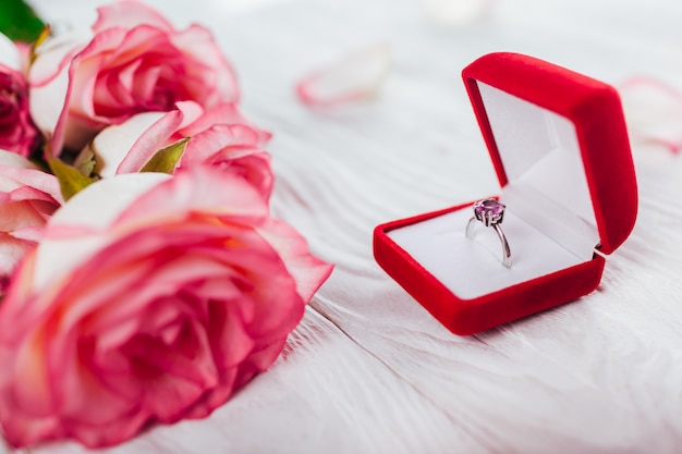 Silver ring with amethyst gem in red gift box and bouquet of roses