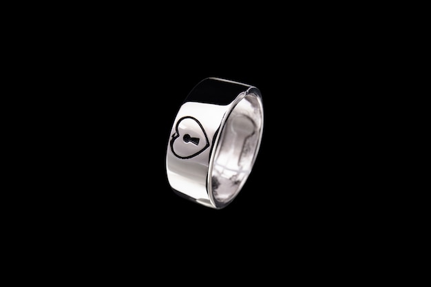 Silver ring with heart and lock on black background