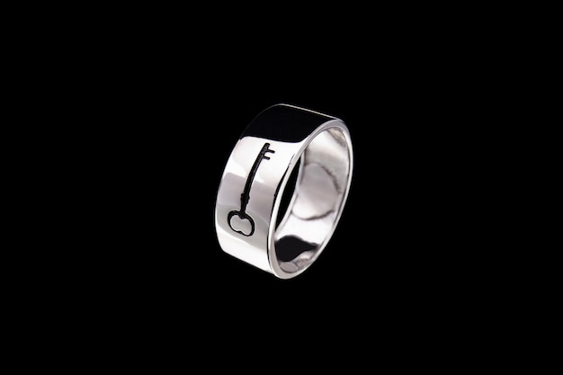 Silver ring with key pattern on black background