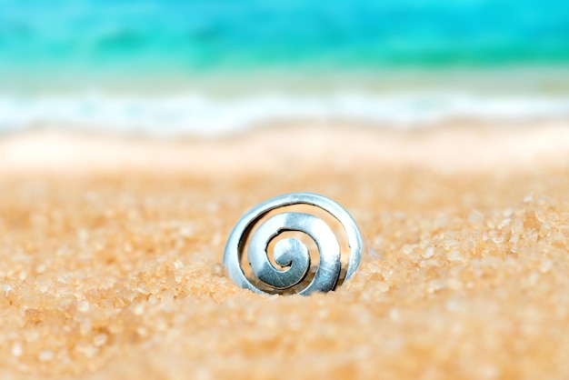 Premium Photo  Silver ring with spiral pattern in the sand on the  background of beach and sea