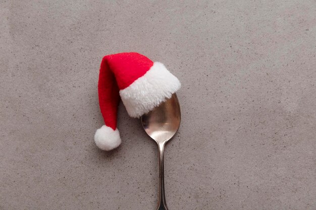 赤いサンタ帽子のクリスマスの食事の背景を身に着けている銀のスプーン
