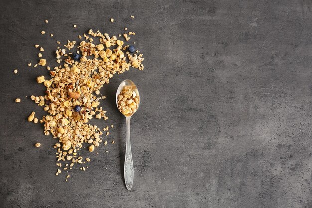 Silver spoon with muesli on gray background