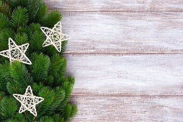 Silver star and decorations on fir branches on a wooden background