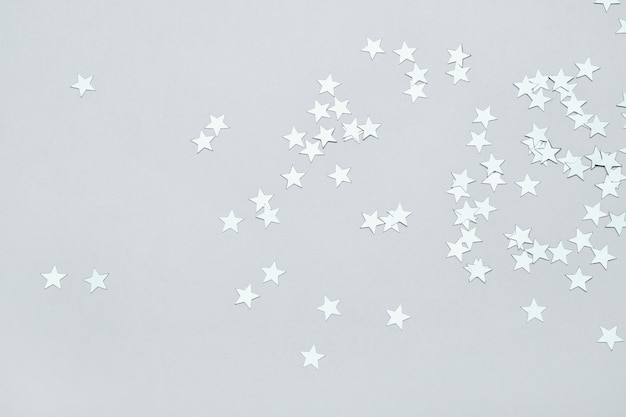 Photo silver stars confetti on gray background christmas or winter festive background