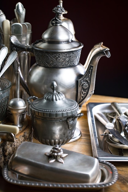 A silver teapot with a design on it is on a table.