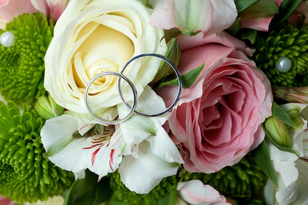 Silver wedding rings lie on flower buds