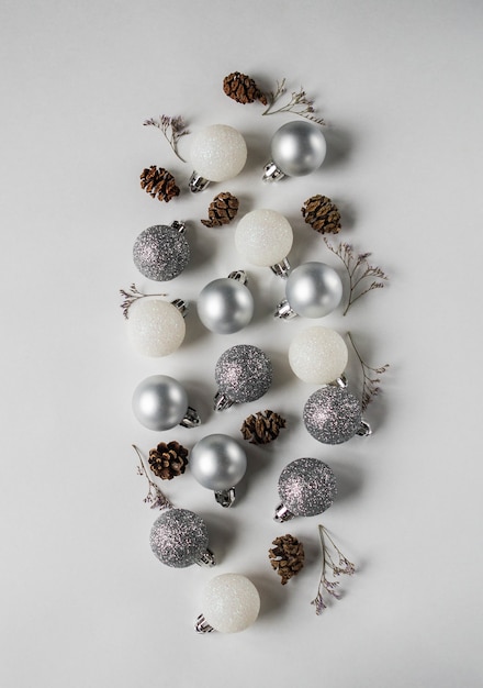 銀と白のクリスマスボール、コーン、ドライフラワーブランチフラットレイアウト。白色の背景