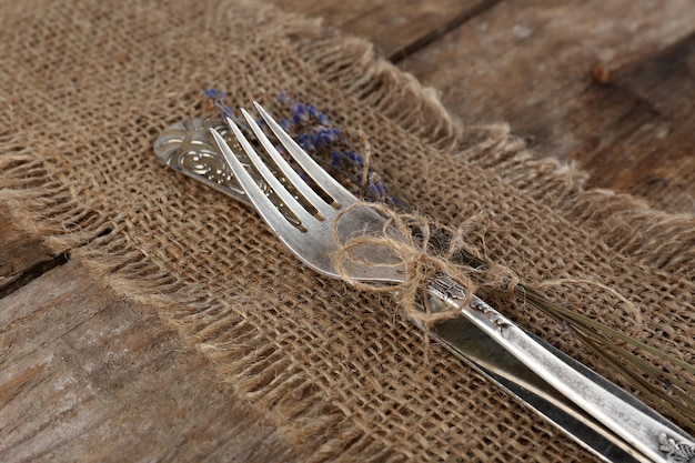 Silverware tied with rope burlap cloth and rustic wooden planks background