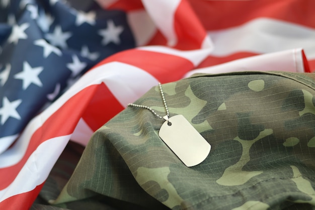 Photo silvery military beads with dog tag on united states fabric flag and camouflage uniform