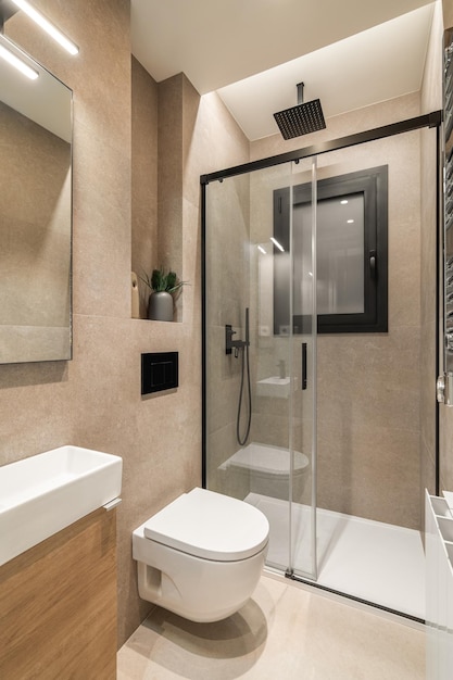 Simple bathroom with black shower white toilet wooden furniture and beige tiles modern interior of