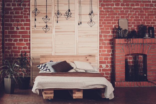 Simple bedroom with double bed, red brick wall and big window