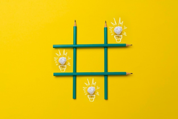 A simple creative idea of drawn paper light bulbs in the tic tac toe grid made of crayons on pastel background