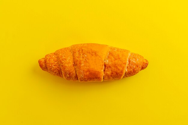 A simple croissant isolated against the colrful surface, traditional french food, minimalism concept