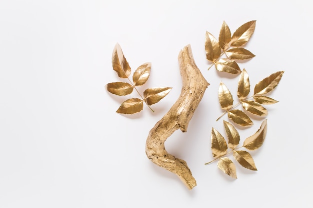 Simple decorative composition with a golden wooden curved stem and golden-colored leaves