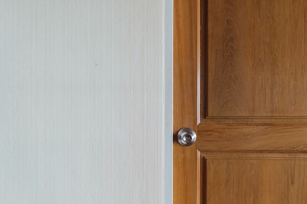 Simple door knob of a wooden door with empty wall.