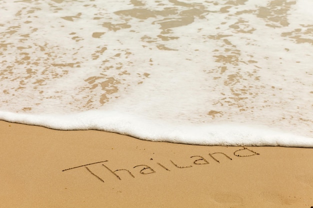 Simple drawing of word Thailand in the sand of the beach