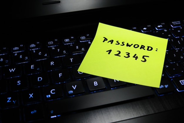 Simple, easy to remember password written on a piece of paper lying on a laptop keyboard.