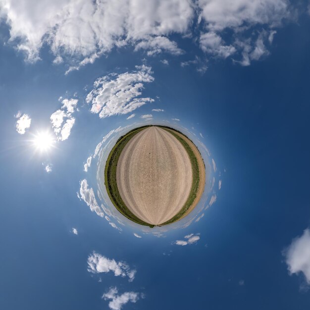 Photo simple green tiny planet without buildings in blue sky with beautiful clouds transformation of spherical panorama 360 degrees spherical abstract aerial view curvature of space