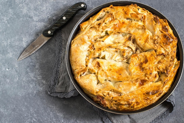 Photo simple homemade pie made of puff pastry with cheese and herbs