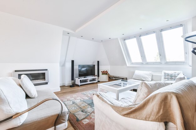 Simple interior of light living room with gray sofa and dining table against