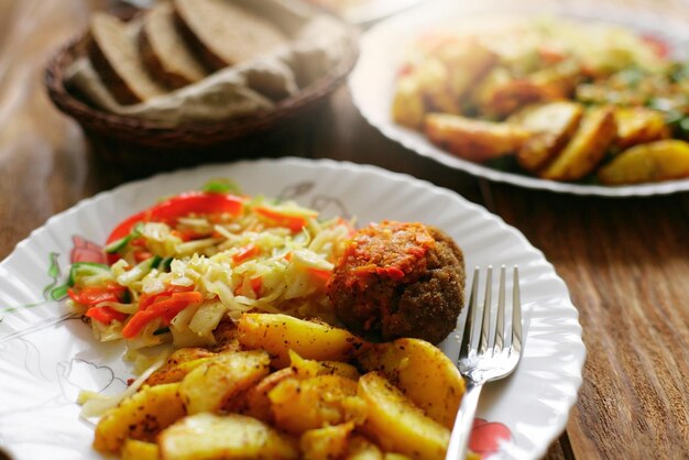 A simple meal on a plate at a diner salad fried potatoes and\
meat cutlet quick and delicious lunch