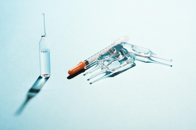 Simple medicine concept still life Ampules and a syringe on blue background