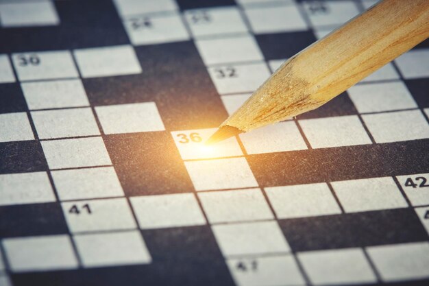 Simple pencil on background of closeup crossword puzzle with bright illumination