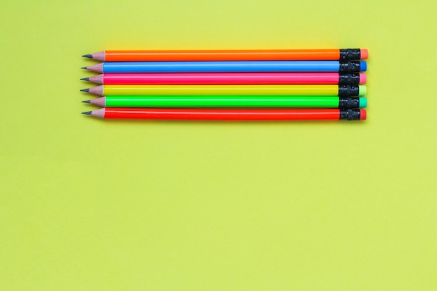 Foto colore al neon delle matite semplici su fondo giallo