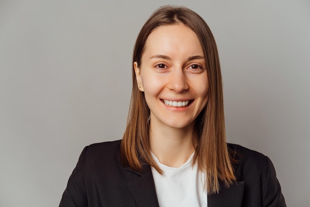 Simple portrait of a handsome smiling young woman over grey background