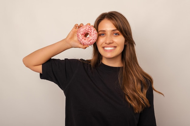 Simple portrait of a smiling blonde woman holding a donut close to her face