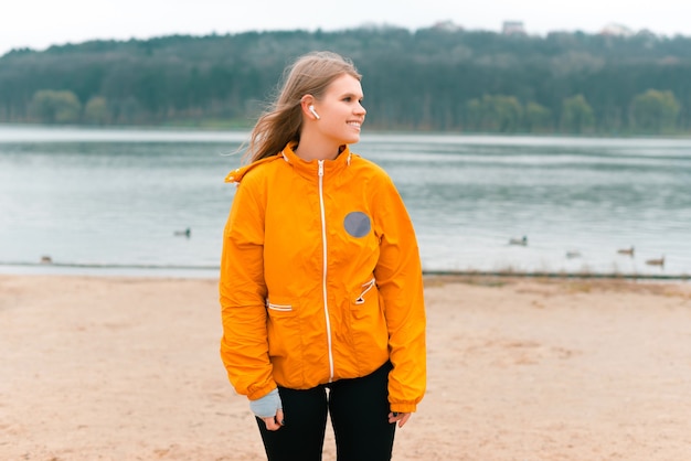 Simple portrait of a young woman wearing sportswear, standing near a lake.