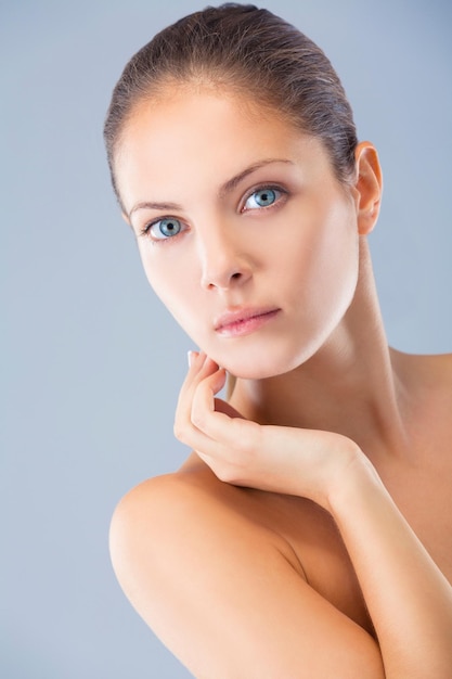 Photo simple and pure. head and shoulders studio shot of a beautiful young woman against a blue background.