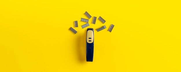 A simple stapler and staples isolated on the colorful surface in office table wide long banner