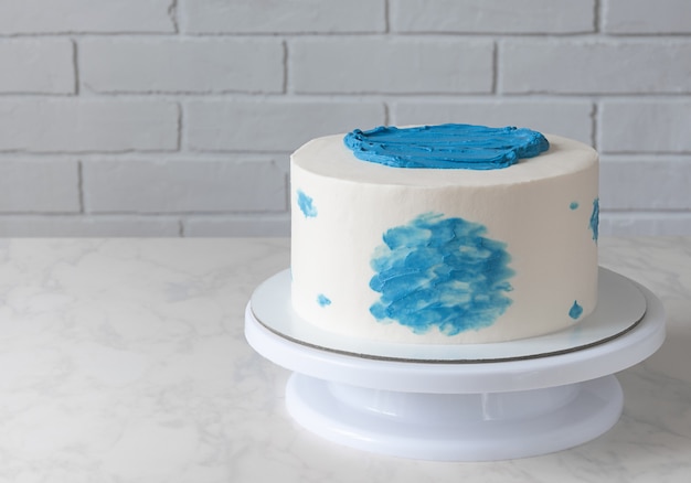 Premium Photo | Simple white cake with blue decor on table.