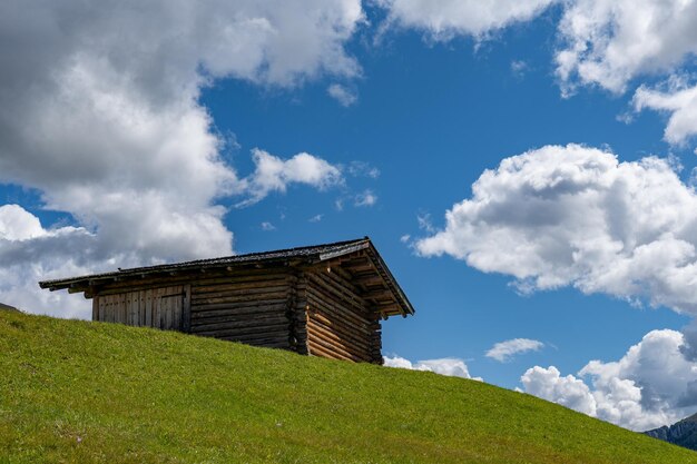 Simple wooden abandoned hut on top of the hill beneath the blue\
sky in the dolomites italy