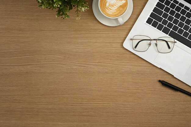 Simple workplace laptop computer eyeglasses and coffee cup on wooden table Flat lay Top view with copy space