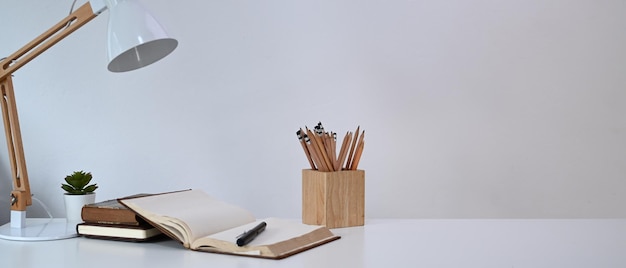 Photo simple workplace with lamp pencils holder notebook and cactus on white desk at home office