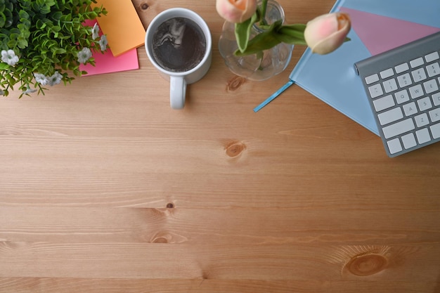 Simple workspace with coffee cup notebook sticky notes and keyboard on wooden desk