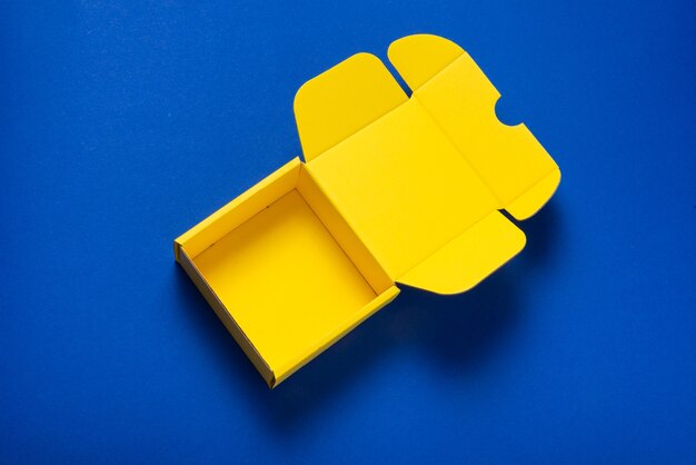 Simple yellow cardboard box on color background, empt inside, opened